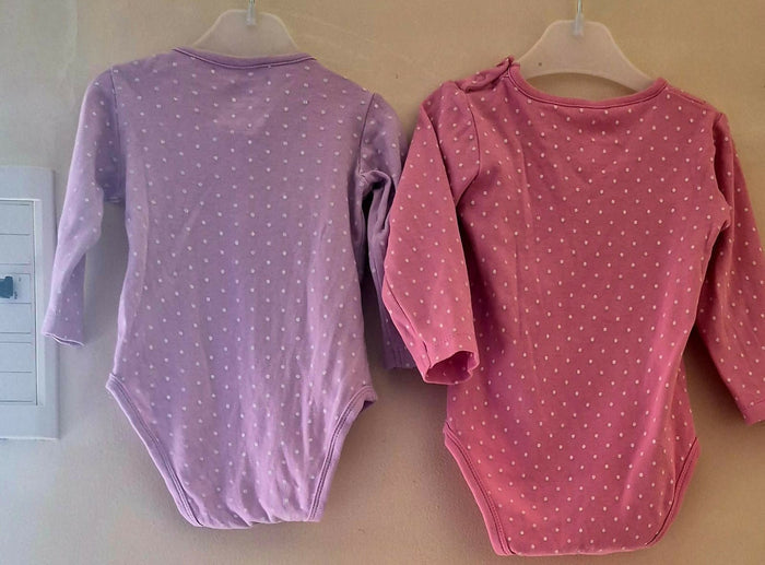 Two baby bodysuits, one purple and one pink, with white polka dots