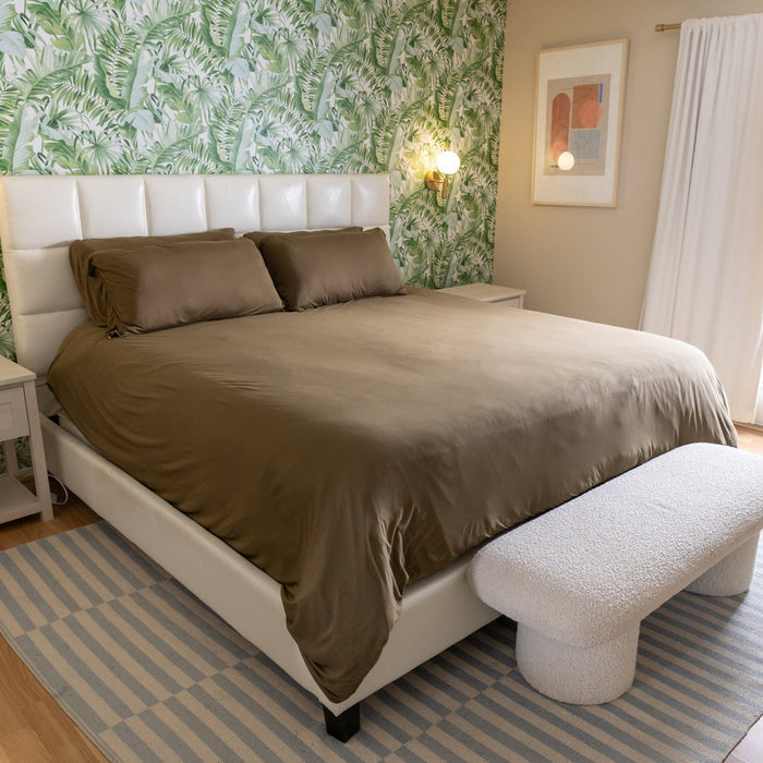 Bedroom with a bed, footstool, and floral wallpaper